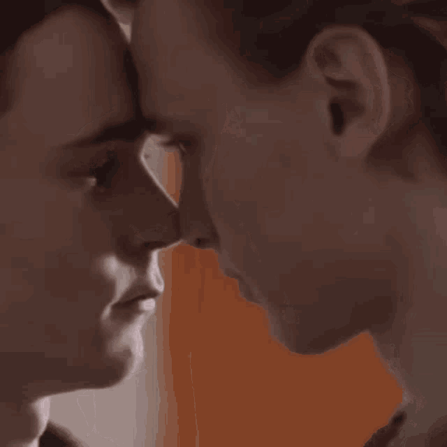a couple of men are kissing each other on the nose .