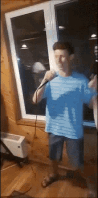 a man in a blue shirt singing into a microphone
