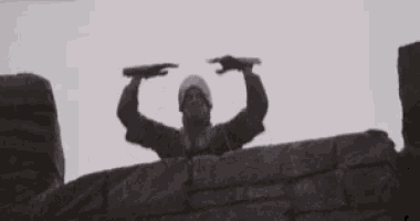 a man in a knight 's armor stands on top of a stone wall