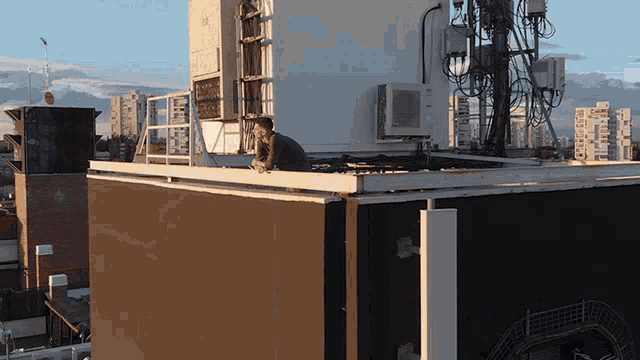 a man sits on a balcony on top of a building with a large white box that says m on it