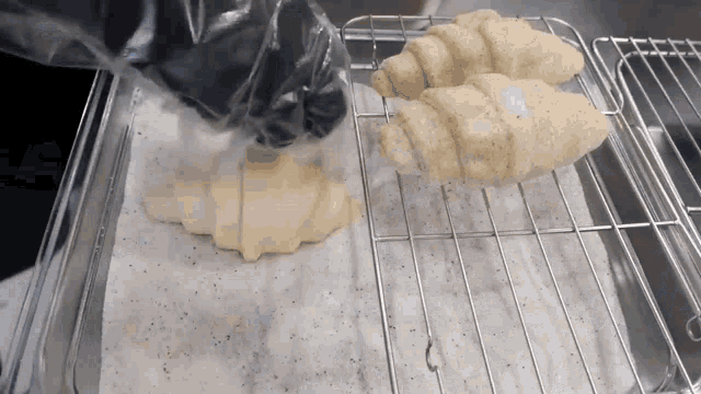 two croissants are sitting on a wire rack on a paper towel .