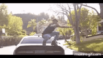 a man is squatting on top of a dodge challenger