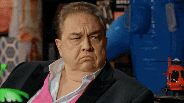 a man wearing a pink shirt and a black suit looks at the camera