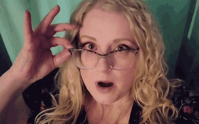 a blonde woman wearing glasses is making a face