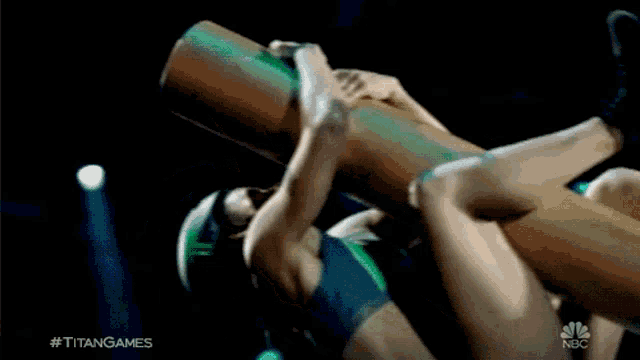 a woman is laying on her back holding a large object with the hashtag #titangames on the bottom