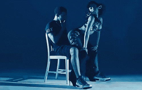 a man is sitting on a chair next to a woman in a bikini who is wearing high heels .