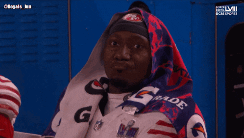 a man wrapped in a gatorade blanket looks at something
