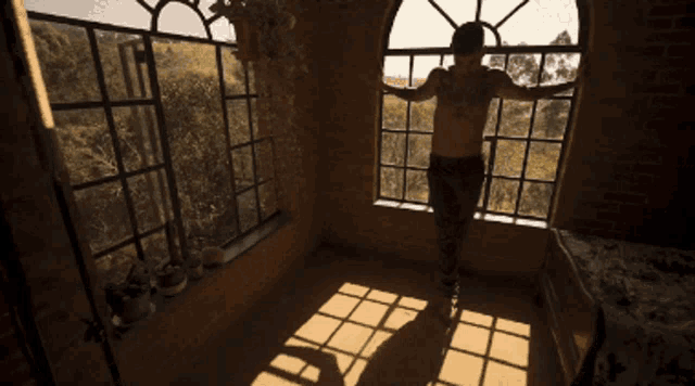 a man without a shirt is standing in front of a large window