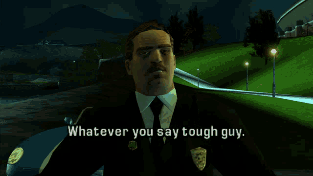 a man in a suit and tie is standing in front of a car and says " whatever you say tough guy "
