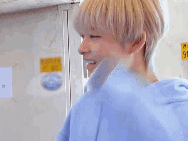 a young man wearing a blue hoodie is smiling while holding his hair .