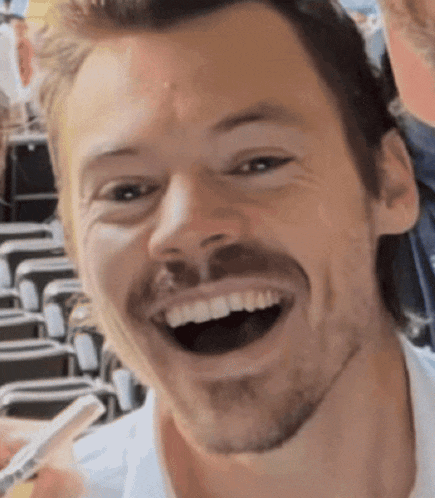 a man with a beard is smiling with his mouth open and holding a pen in his hand .