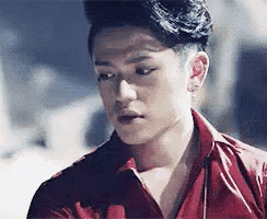 a close up of a man wearing a red shirt and earrings .