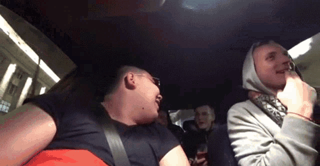 a group of people are sitting in the back seat of a car laughing and talking .