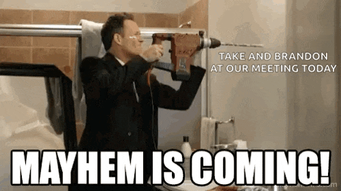 a man in a suit is holding a drill in his hand and says mayhem is coming !