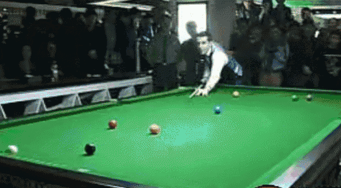 a man is playing snooker in front of a crowd with a cue in his hand