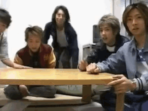 a group of people are sitting around a table and one of them is wearing a jacket with the letter a on it