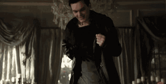 a man in a black coat is standing in a living room