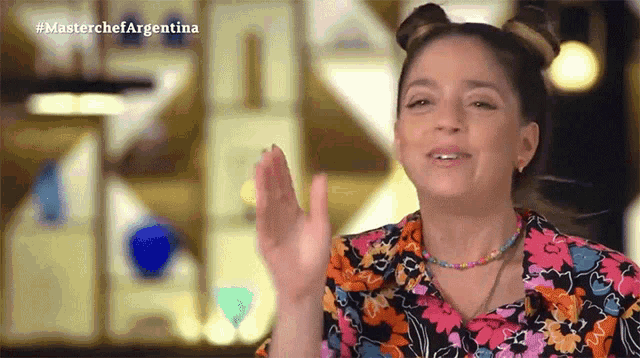 a woman in a floral shirt is giving a high five in a video for masterchef argentina