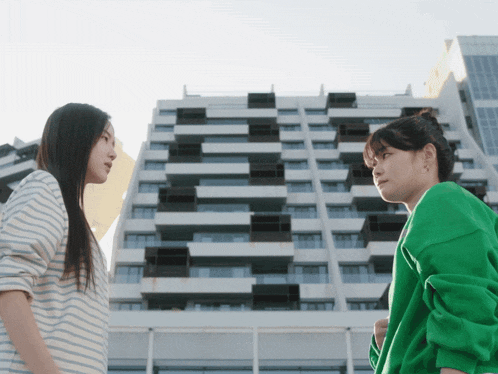 a woman in a green sweatshirt stands next to another woman in a striped shirt