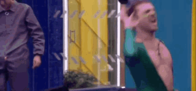 a shirtless man is standing in front of a colorful door .