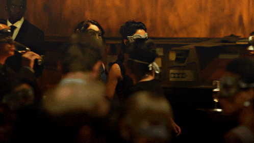 a woman in a white mask stands in a crowd