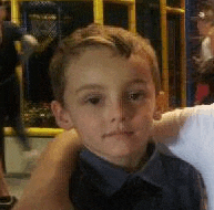 a young boy in a blue shirt is being held by a person in a playground .