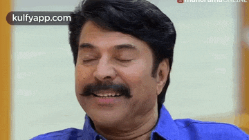 a man with a mustache is laughing with his eyes closed and his mouth open .