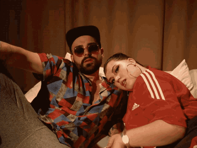 a man and a woman are posing for a picture the woman is wearing an adidas shirt