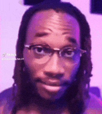 a man wearing glasses and dreadlocks is making a funny face