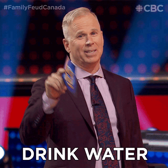 a man in a suit and tie is holding a piece of paper and says drink water