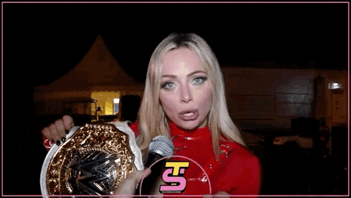 a woman in a red sweater is holding a wrestling belt in her hands .