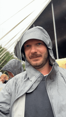 a man with a beard wearing a grey raincoat