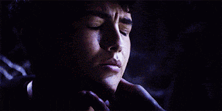 a close up of a young man 's face with blue eyes in the dark .
