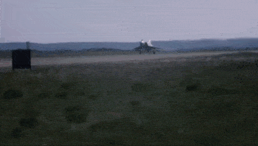 a plane is taking off from a runway in a field