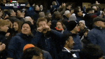 a crowd of people are standing in a stadium watching a game .