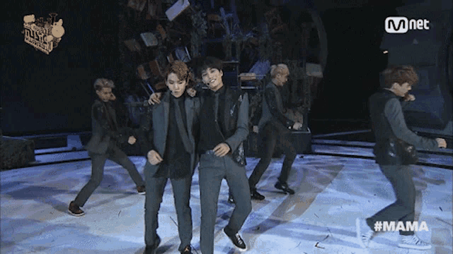 a group of men are dancing on a stage with a mnet logo behind them