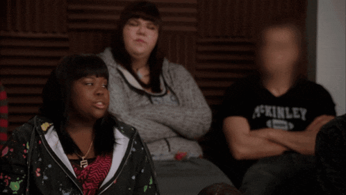 a group of people are sitting in a room and one of them is wearing a shirt that says ' kinley ' on it