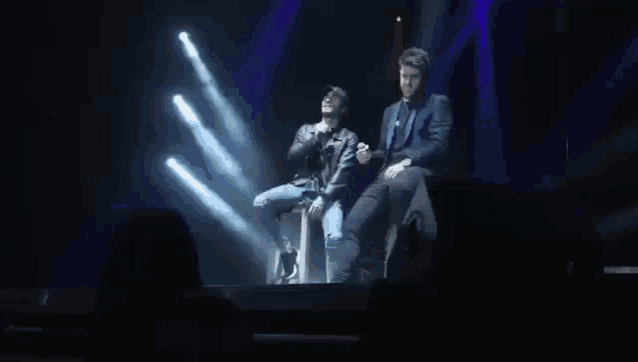 a man singing into a microphone while another man sits behind him with the name diogo picarra on the bottom