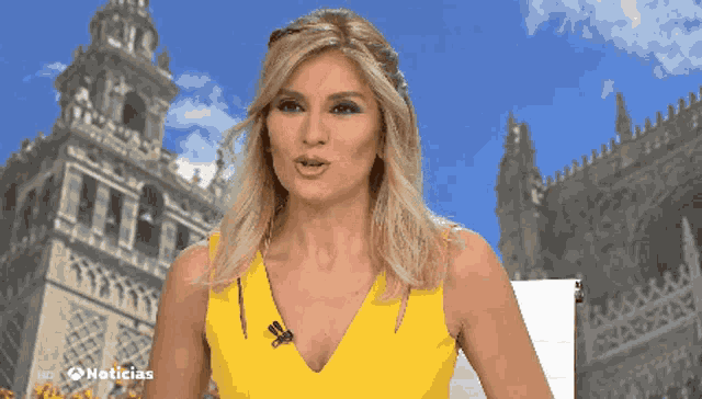 a woman in a yellow dress is standing in front of a building that says noticias on it
