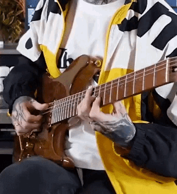 a man with tattoos is playing an electric guitar .