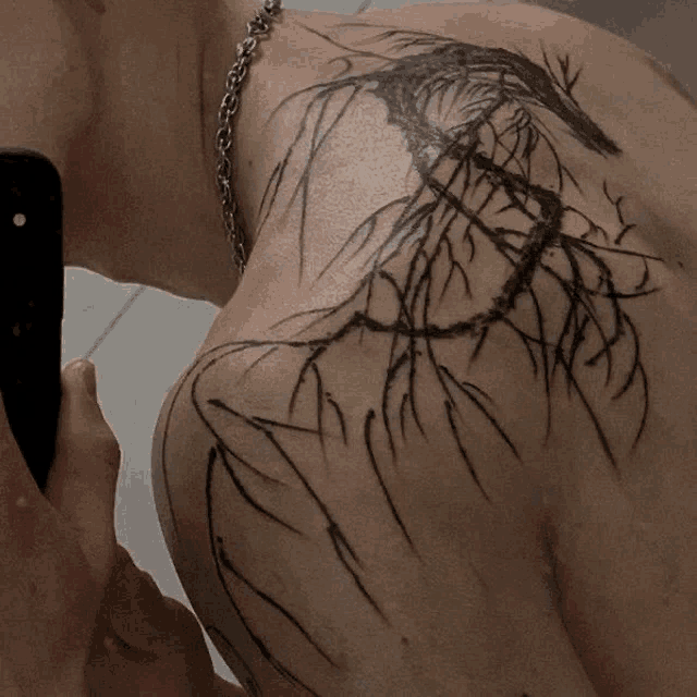 a person with a tattoo on their back is taking a selfie with their phone