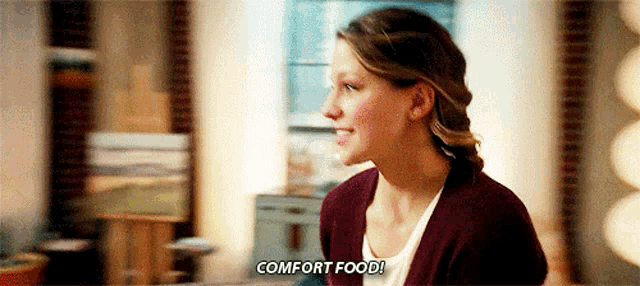 a woman is sitting on a couch in a living room and talking about comfort food .