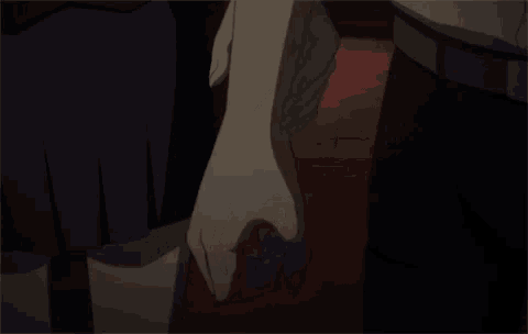 a man and woman are holding hands in a dark room .