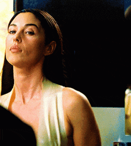 a woman in a white tank top is looking at herself in the mirror