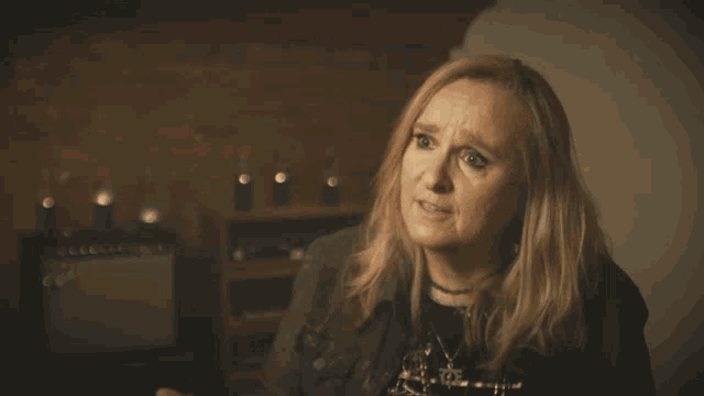 a woman with blonde hair is wearing a black jacket and a choker around her neck