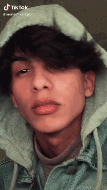 a young man wearing a hoodie and a denim jacket .