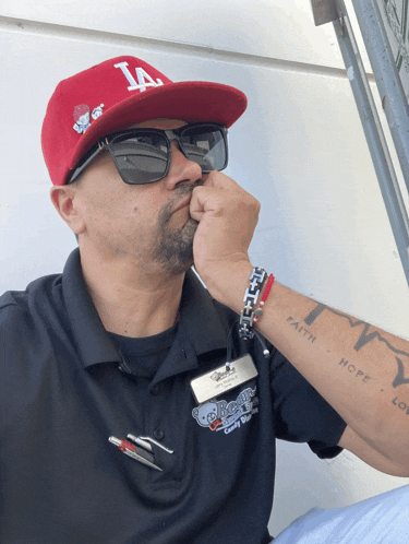 a man wearing a la hat and sunglasses is covering his mouth