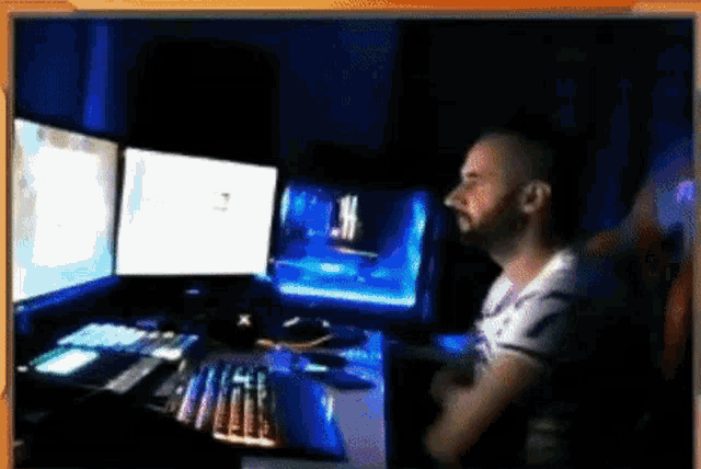 a man is sitting in front of a computer with three monitors .