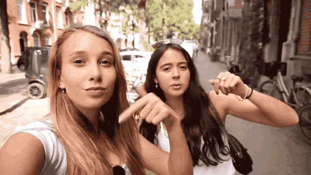 two young women are standing next to each other on a street