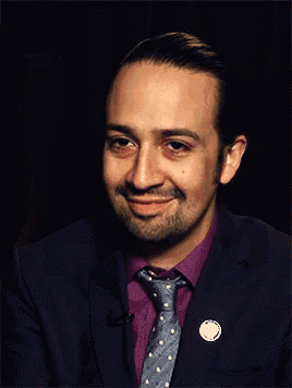 a man with a beard wearing a suit and tie smiles for the camera